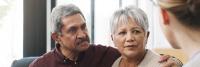 Middle aged couple sit listening to doctor during visit.
